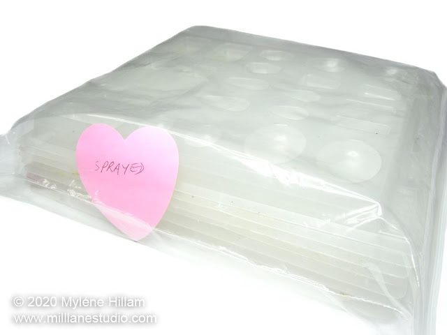 A stack of sprayed plastic mould trays inside a ziplock bag