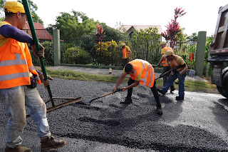 Group of people applying new asphalt to road in Puriscal.