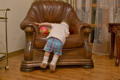 a small girl is in front of the arm chair