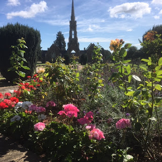 Chapel with a spire framed by lots of colourful blooming flowers