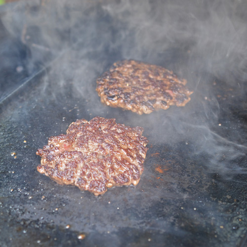 Smash burger patties on the griddle on a Big Green Egg