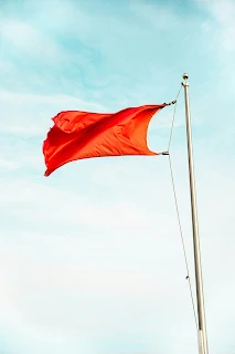 A singular red flag flying in the wind. Warning!