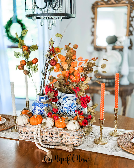 orange spiral tapers in thrifted brass candlesticks and basket filled with pumpkins and ginger jars