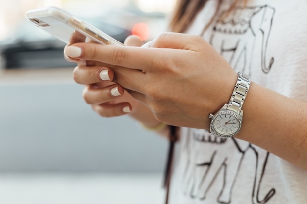 Mão feminina segurando um celular Iphone nas mãos