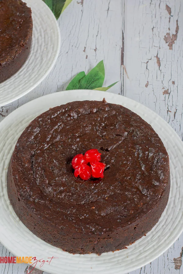 Finished black cake with red cherries on a white plate