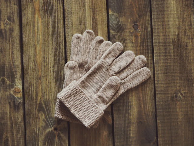 Flat lay shot of a pair of gloves against a wooden surface.