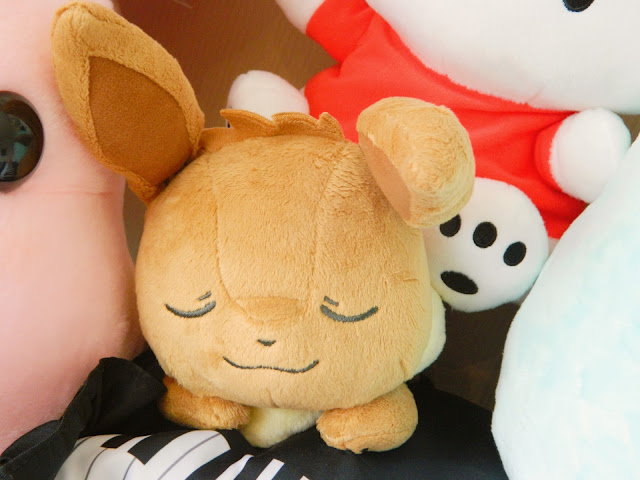 A photograph of a sleeping fox-looking Pokemon plush