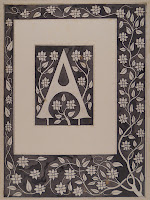 A printed capital "A," backed and framed a a flowering branch grows around the border of the print.