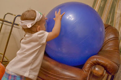 a small girl in front of a a blue fit ball