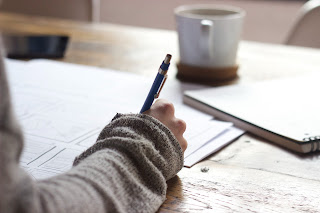 person studying at table with books and a mug