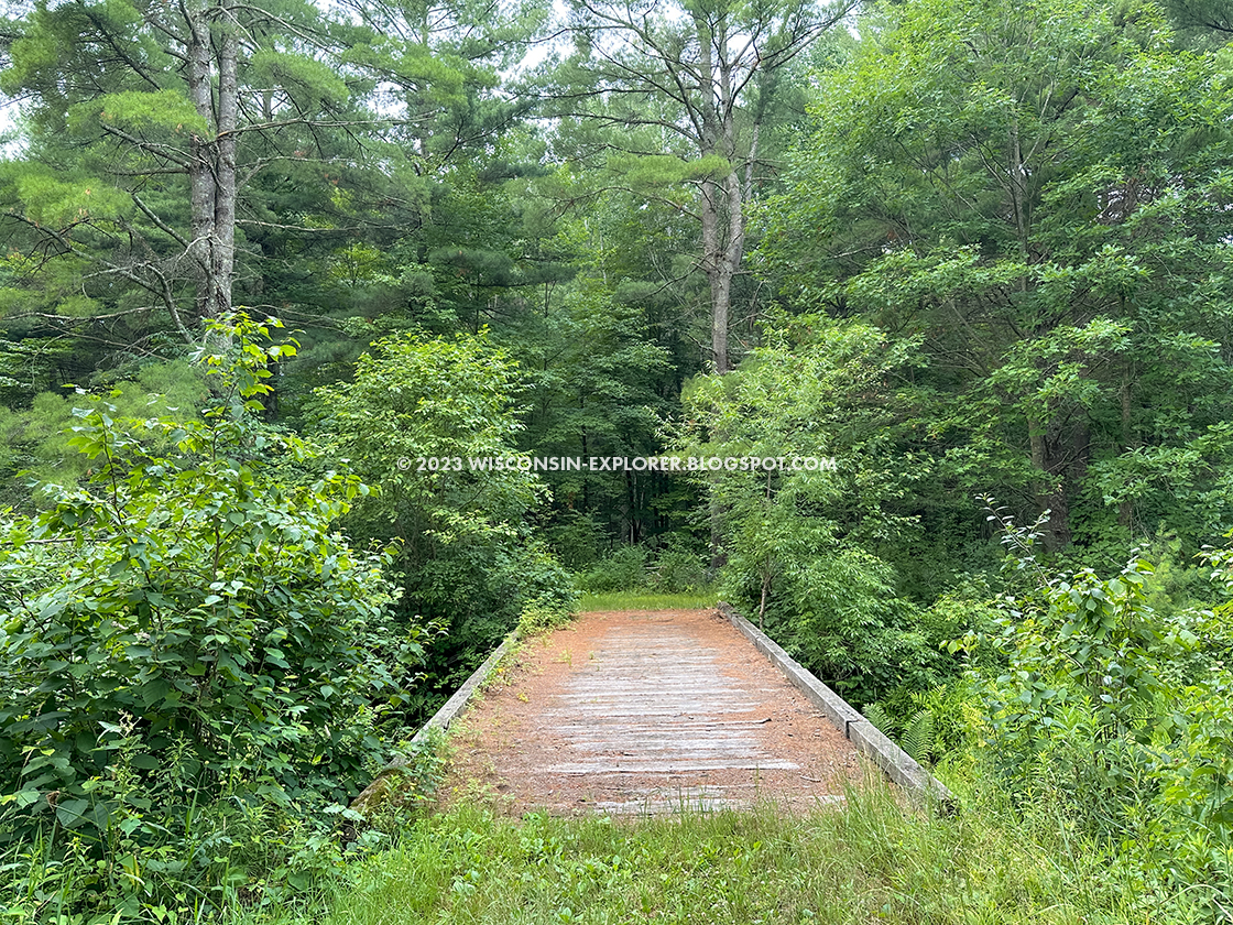 wide wood plank pedestrian bridge across stream