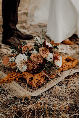 Novios con una alfombra a sus pies y un chal y flores con tonos otoñales