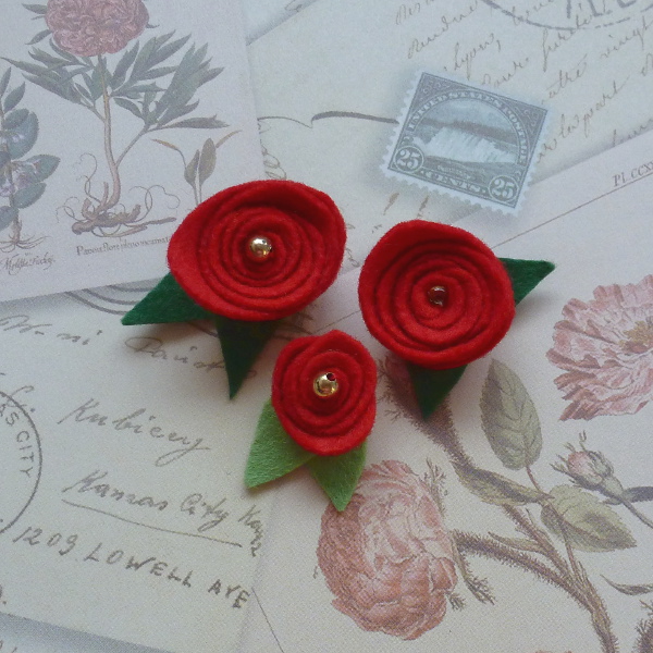 iny red felt roses with beads and green leaves on floral paper background learn how to sew and make small felt rose flowers