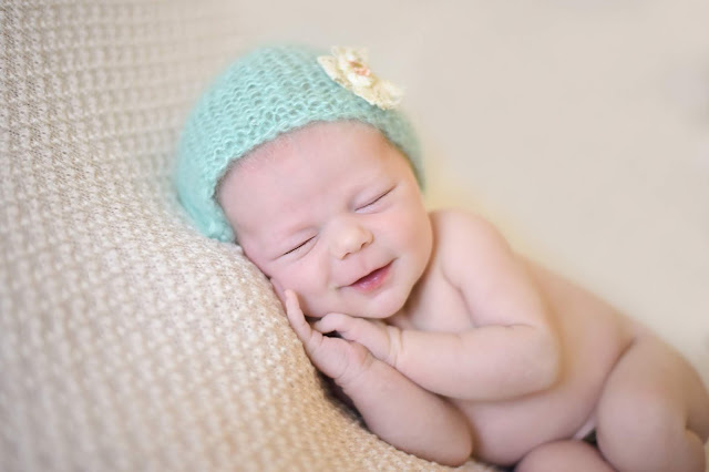 newborn girl on creme blanket and blue hat