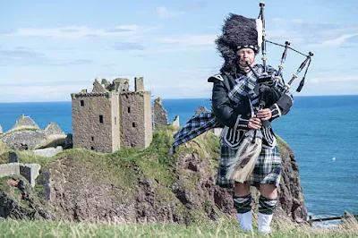 Tradicional bagpiper escocês no Castelo de Dunnottar