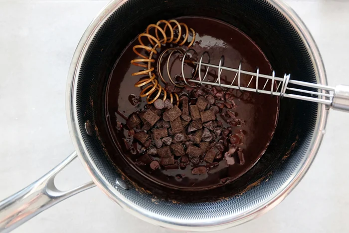 adding chocolate to cooked hot fudge ingredients
