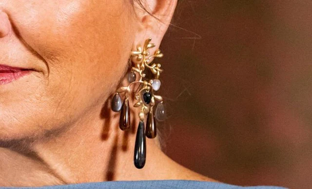 Queen Maxima wore a sky blue silk cape dress by Natan. She wore a wool camel coat. Ole Lynggaard gipsy earrings