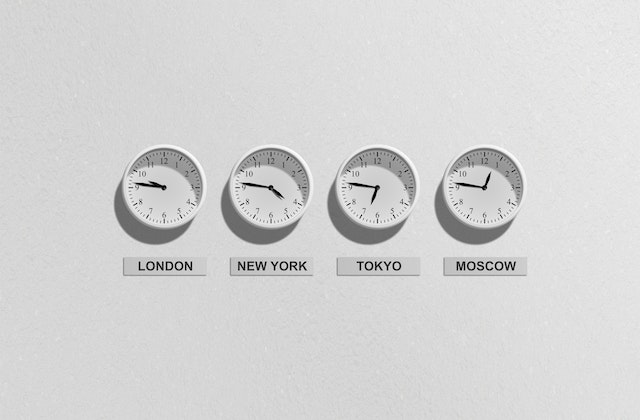 Four wall clocks showing different time zones