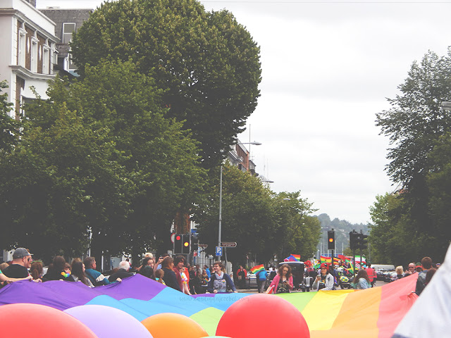 a parade of people holding the lgbti flag marching