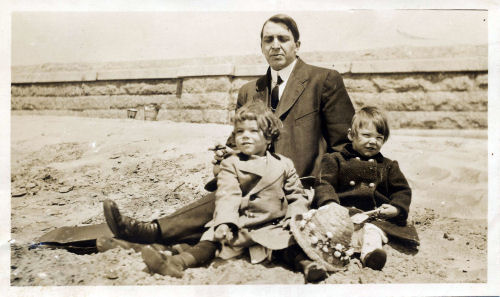 man with two children on a beach in 1911