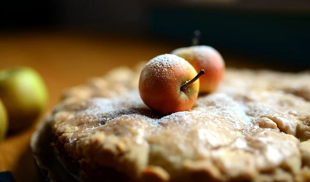 An apple pie with two aples sitting on top of it.