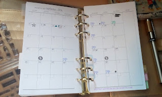 The image of a two page spreed month calendar with several letters and symbols stamped onto it.  