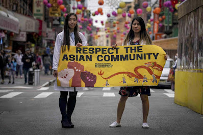 Dr. Michelle Lee, left, a radiology resident, and Ida Chen, right, a physician assistant student, unfold a banner Lee created to display at rallies protesting anti-Asian hate, Saturday April 24, 2021, in New York's Chinatown- Photo Credit -AP