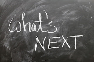 A chalkboard, with "what's next" written on it in white chalk
