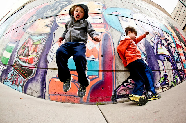 Two little boys jumping and dancing in front of a David Choe mural in Denver, Colorado.