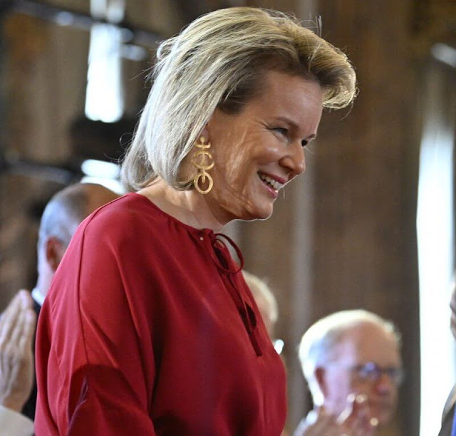Queen Mathilde wore a red silk blouse and pattern midi skirt. Elman Peace of Somalia and King Baudouin Foundation