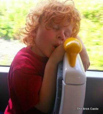 my youngest son sleeping on the tram , sitting up on his knees, with his face over the back of the seat