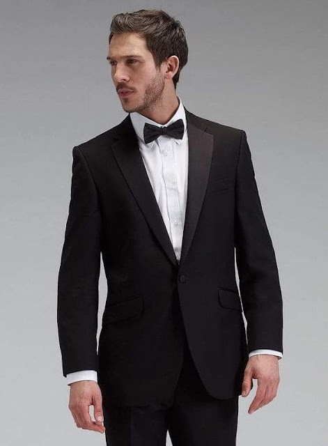 Black suit, plain white shirt, black bow tie, and one button on the jacket.