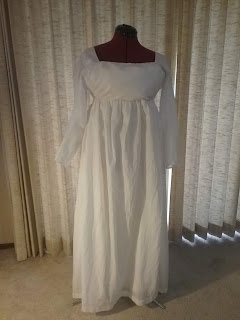 High-waisted white dress with long, slim sleeves, and a wide open neck.