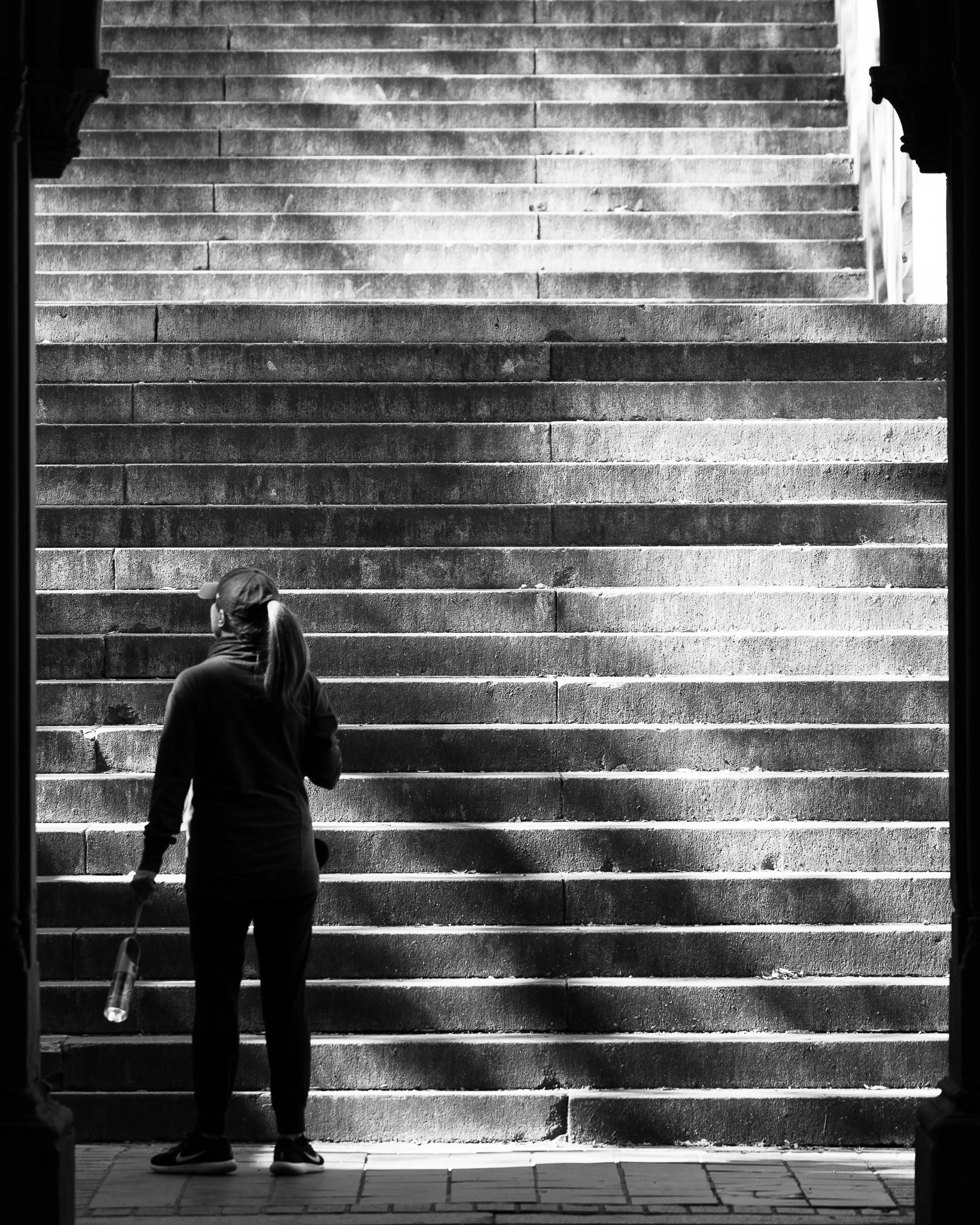 a black and white photo of a woman on a staircase at bethesda terrace new york city