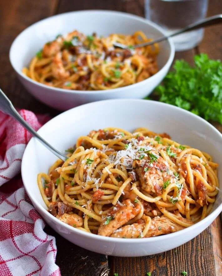 Dos tazones servidos con pasta con pollo en salsa de tomate