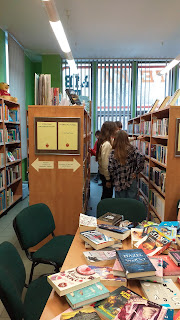 Młodzież ogląda biblioteczne ksiażki na półkach.