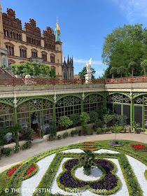 The iron-clad decorated orangery of a castle under a bright blue sky.