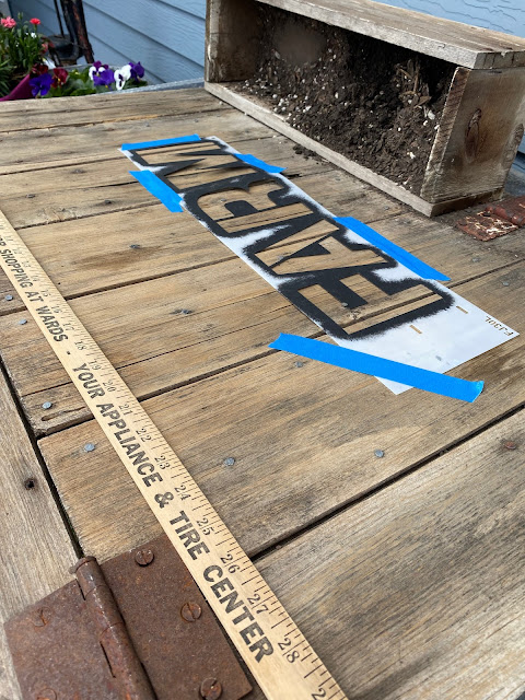 Photo of measuring & taping a stencil on an old barn door.