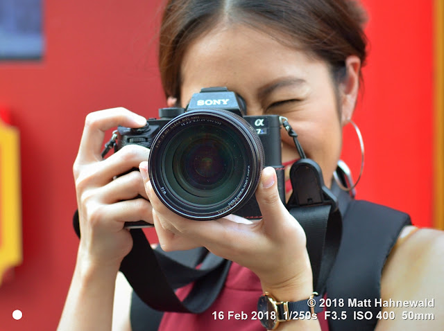 matt hahnewald photography; facing the world; real; live; aesthetic; head; facial expression; camera; sony alpha 7s; mirrorless; dirty; both hands; consent; rapport; fun; concept; lifestyle; hobby; goodtime; impact; equity; chinese new year; photographer; yaowarat; chinatown; bangkok; thailand; asia; asian; thai; one person; female; young; woman; photography; image; photo; nikon d3100; nikkor af-s 50mm f/1.8g; prime lens; 50mm; 4x3; horizontal; street; portrait; closeup; head shot; cropped; full-face view; outdoor; color; cool; iconic; awesome; incredible; authentic; positive; beautiful; attractive; charming; fabulous; photographing; taking photo