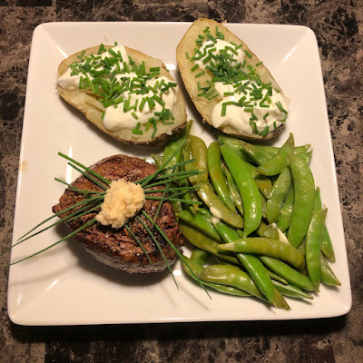 Rare filet mignon, baked potato with sour cream and chives and sugar snap peas