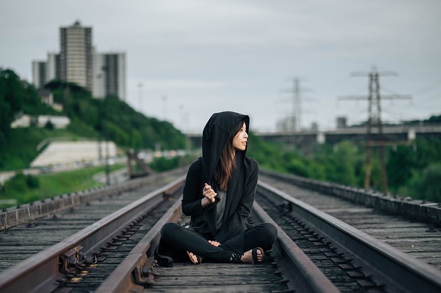 Woman sitting in the middle of train tracks.