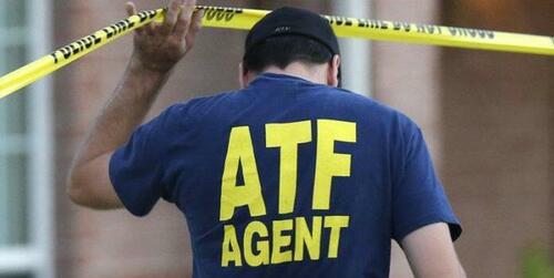 An ATF agent lifts crime scene tape.