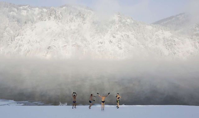 Members of the Dolphin winter swimming club warm up on the bank of the Yenisei River ahead of their ... - REUTERS/Ilya Naymushin