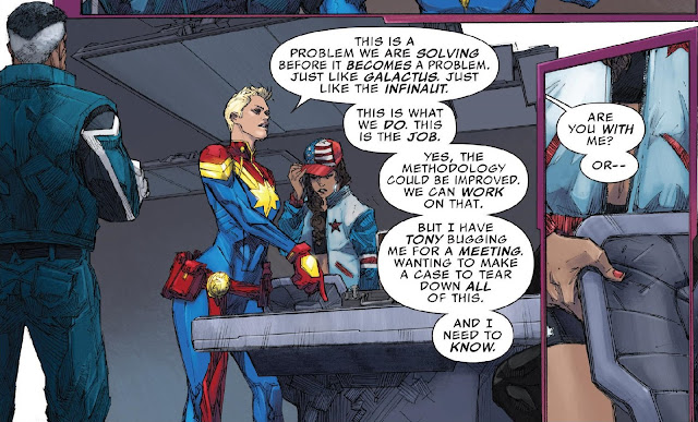 Captain Marvel standing imposingly in front of a table with the empty briefcase on it addressing the team.