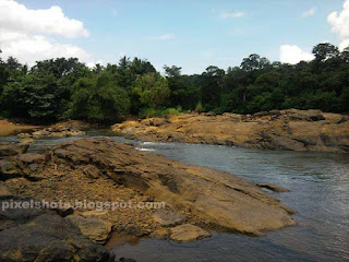 river stream slowing between river bed rocks,huge rocks covering the river landscape seperating the river stream,flowing river between rocks