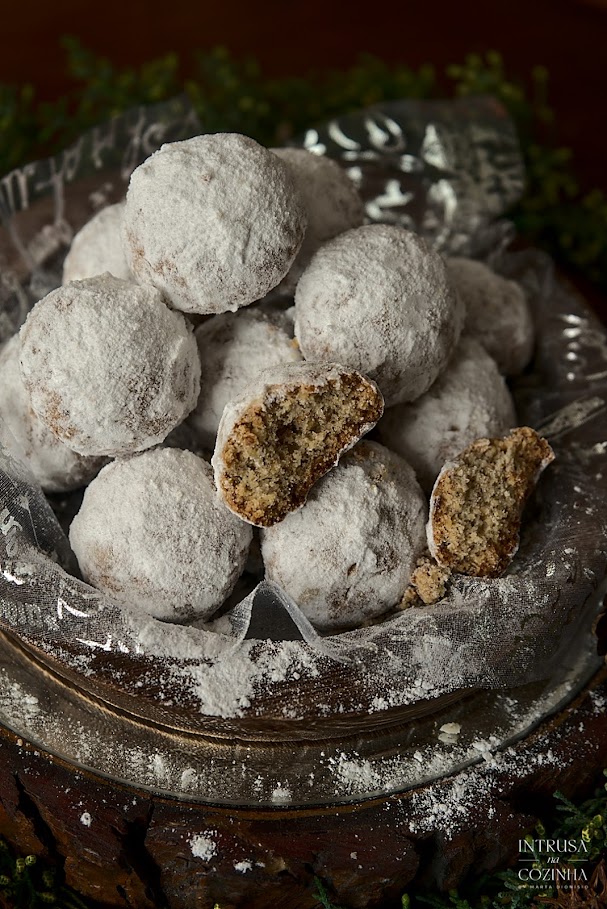 Bolinhos redondos brancos numa bandeja, num cenário escuro, com um bolinho partdo ao meio