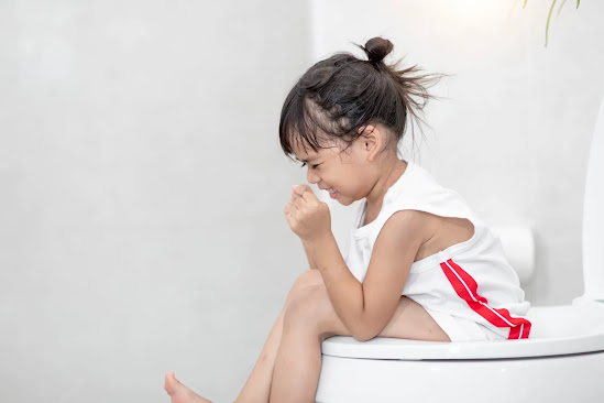A girl child suffering from diarrhea sitting on a commode