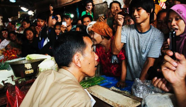 Jokowi sedang berbicara ke pedagang di pasar tradisional