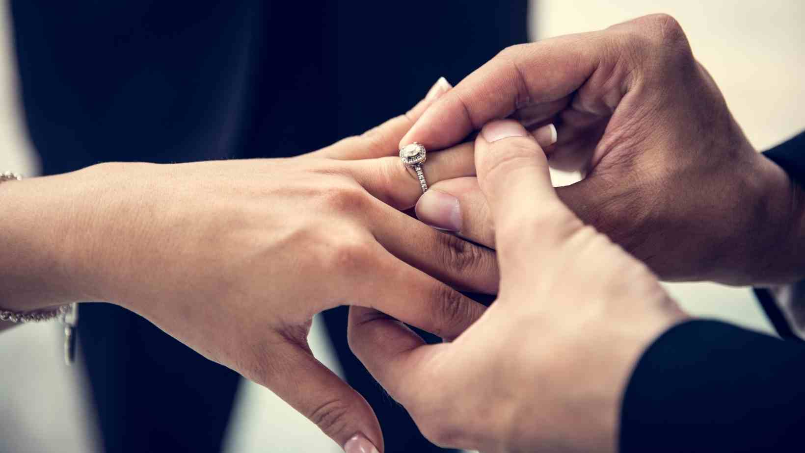 Canva pro stock image showing a close up of a man putting a ring on a woman's hand