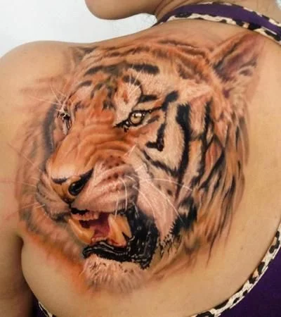 tatuaje de tigre en el omoplato de una señorita que lleva camiseta